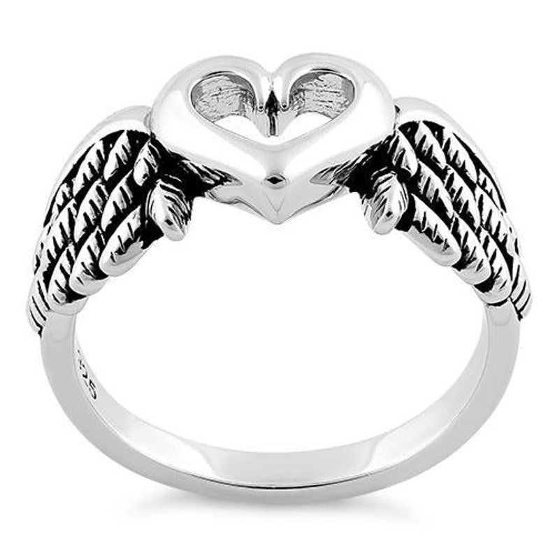 May include: A silver ring featuring a heart-shaped design with open space in the center, flanked by detailed wing accents. The ring has a polished finish and a smooth band.