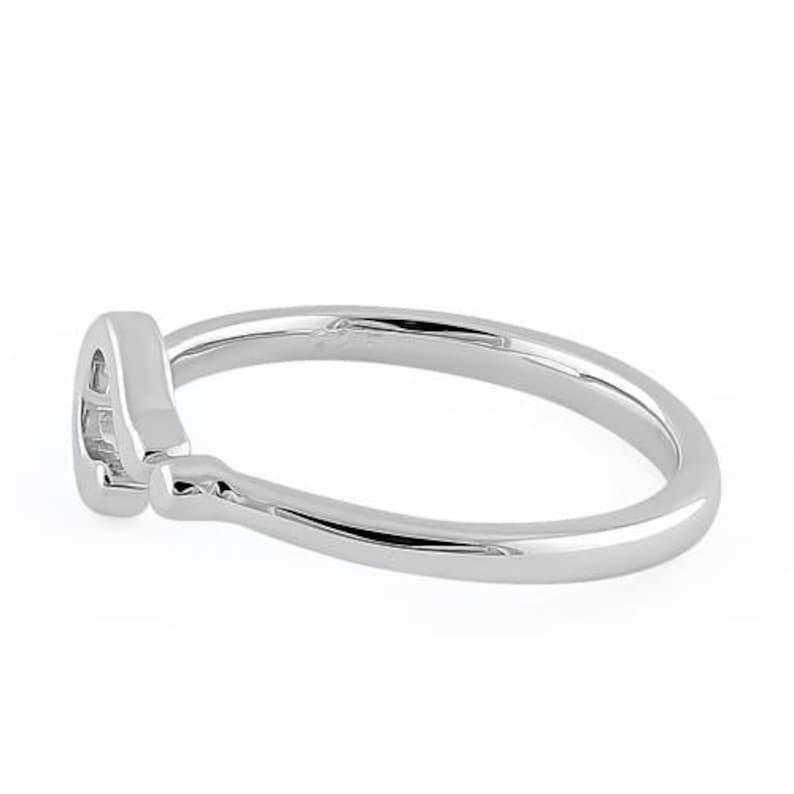 Puede incluir: Un anillo de plata con un dise&ntilde;o simple y curvo. El anillo es liso y pulido.