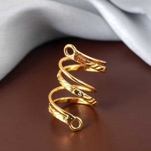 Könnte beinhalten: Ein goldfarbener Spiralring mit einem strukturierten Design. Der Ring ist offen und hat einen schlichten, eleganten Look.
