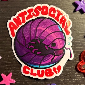 May include: A sticker with the words "ANTISOCIAL CLUB" in red, surrounding a purple and pink pillbug illustration. The sticker is surrounded by star-shaped and flower-shaped embellishments.