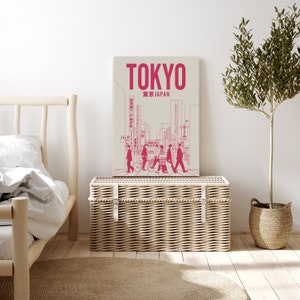 K&ouml;nnte beinhalten: Eine rosa und wei&szlig;e Illustration einer Stra&szlig;enszene in Tokio, Japan. Die Illustration zeigt Personen, die &uuml;ber einen Zebrastreifen gehen, Geb&auml;ude und Schilder in japanischer Sprache. Der Text "TOKYO" und "東京 JAPAN" ist in rosa oben auf der Illustration gedruckt.