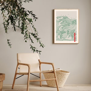 May include: A framed print of a green and white wave design with Japanese text that reads "波濤の宴". The print is hanging on a light gray wall with a wooden chair and a woven basket in the foreground.