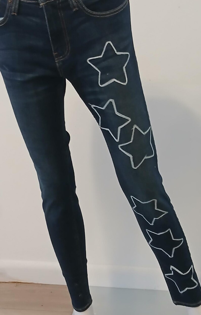 May include: Dark blue denim jeans with white star outlines on the right leg.