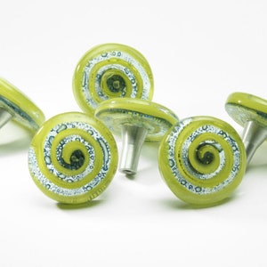 Puede incluir: Cinco pomos de armario de vidrio verde lima con diseños de espiral plateados. Cada pomo tiene un poste de metal plateado.
