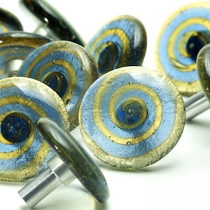 Peut inclure: Un ensemble de boutons de cabinet en verre bleu et or avec un motif en spirale. Les boutons ont une base en métal argenté.
