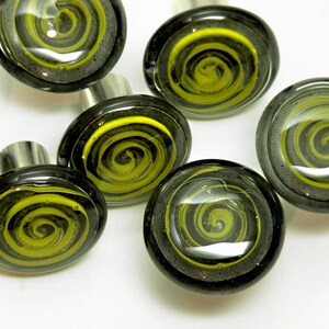 May include: Seven round glass cabinet knobs with a black and yellow swirl design. The knobs have a silver metal base.