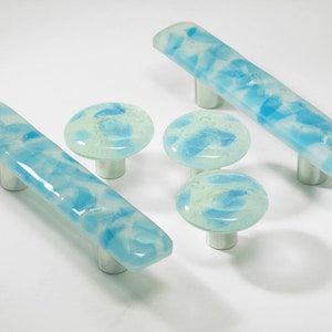 Peut inclure: Ensemble de cinq boutons de cabinet en verre avec un motif marbré bleu et blanc. Les boutons sont de formes variées, notamment rondes et rectangulaires.