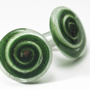 May include: Two green glass swirl design bottle stoppers with a white swirl in the center.