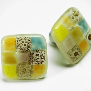 Può includere: Due pomelli quadrati per armadi in vetro con un motivo a mosaico di quadrati gialli, blu chiaro, rosa e marroni. I pomelli hanno una base in metallo argentato.