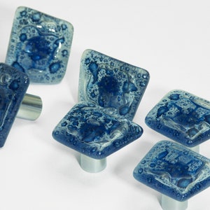 Può includere: Set di sei pomelli per armadi in vetro blu e bianco con un design unico, testurizzato e maculato. Ogni pomello ha una base in metallo argentato.