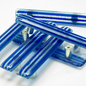 Könnte beinhalten: Ein Satz von fünf blauen und weißen, gestreiften Glas-Schrankknöpfen mit silberner Metallbeschläge.