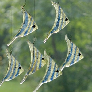 May include: A glass mobile with six blue and yellow fish shapes hanging from strings. The fish are translucent and have a striped pattern.