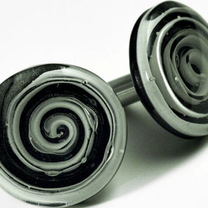 Peut inclure: Une paire de boutons de manchette en verre noir et blanc avec un motif en spirale.