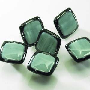 Puede incluir: Seis pomos de armario cuadrados de vidrio con borde negro y centro verde claro. Los pomos tienen una superficie ligeramente texturizada.