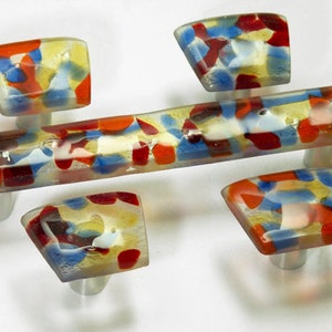 Peut inclure: Ensemble de cinq boutons de cabinet en verre avec un motif de mosaïque coloré dans des tons de rouge, bleu, jaune et blanc. Les boutons sont montés sur des bases argentées.