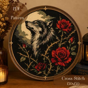 Könnte beinhalten: Ein kreisförmiges Kreuzstichmuster mit einem Wolfsprofil vor einem Vollmond, umgeben von roten Rosen und dornigen Ranken auf schwarzem Grund. Das Design ist in einem runden Holzrahmen mit Sternakzenten gefasst und enthält den Text PDF Pattern.