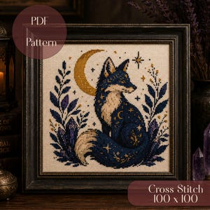 Pode incluir: Um padrão de ponto cruz emoldurado com uma raposa azul-escura sentada diante de uma lua crescente dourada. O design inclui folhagem roxa, formas de cristal e estrelas em tecido creme. Texto: PDF Pattern e Cross Stitch 100 x 100.