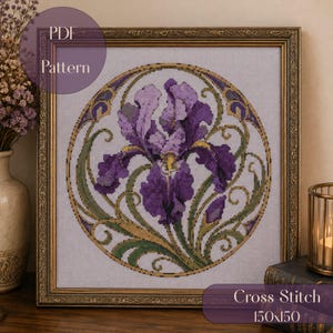 Könnte beinhalten: Ein gerahmtes Kreuzstichmuster mit einer zentralen violetten Irisblume in einem kreisförmigen dekorativen Rahmen. Das Design umfasst grünes Blattwerk und goldene Akzente auf hellem Stoff. Der Text PDF Pattern und Cross Stitch 150x150 ist zu sehen.