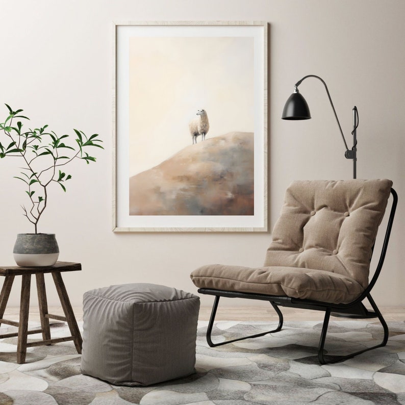 May include: A framed watercolour painting of a white sheep standing on a hill. The painting is hanging on a white wall above a brown ottoman and a black metal chair with a beige cushion.