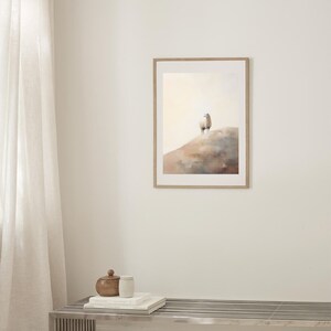 May include: A framed watercolour painting of a white sheep standing on a hilltop. The background is a soft, muted orange and blue.
