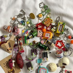 Könnte beinhalten: Ein Set aus drei Keramikbechern mit gesprenkelter, matter Oberfläche. Die Becher sind in Creme-, Hellgrau- und Dunkelgrautönen gehalten. Jeder Becher hat ein schlichtes, minimalistisches Design.