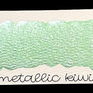 May include: A swatch of metallic kiwi watercolor paint on a white card. The card has the number "119" written at the top left and the words "metallic kiwi" at the bottom. The paint has a textured, shimmering appearance.