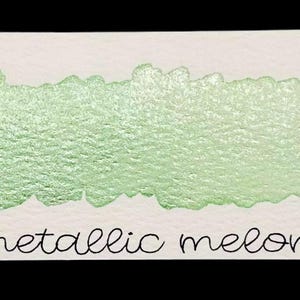 May include: A rectangular swatch of metallic melon watercolor paint on white paper. The paint is a shimmering, light green color. The text "no. 109" is written in black script at the top left, and "metallic melon" is written in script at the bottom.