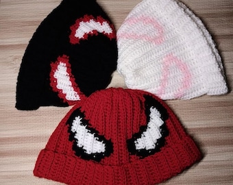 May include: Three crocheted hats, one black with white accents, one white with pink accents, and one red with black and white accents.