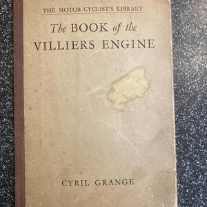 May include: A vintage book titled "The Book of the Villiers Engine" by Cyril Grange. The cover is a faded tan colour with a brown spine. The text "The Motor-Cyclist's Library" is printed at the top. The book shows signs of wear and age.