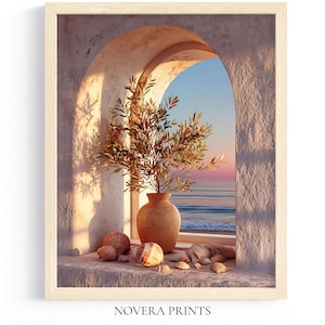 Puede incluir: Impresión enmarcada que presenta una escena costera serena. Un jarrón con ramas de olivo se encuentra en una ventana, con conchas marinas en el alféizar. El texto "NOVERA PRINTS" está en la parte inferior. El cielo transita de azul a rosa sobre el mar.