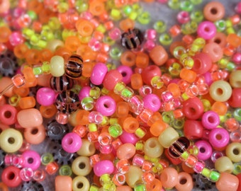 以下が含まれることがあります： ピンク、オレンジ、イエロー、グリーンの色合いのカラフルなプラスチックビーズのクローズアップ。ビーズはランダムなパターンで配置されており、クラフトプロジェクトに最適です。