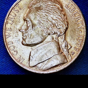 May include: A gold-colored US nickel coin with the profile of Thomas Jefferson on the obverse. The coin reads "IN GOD WE TRUST" and "LIBERTY 1969".