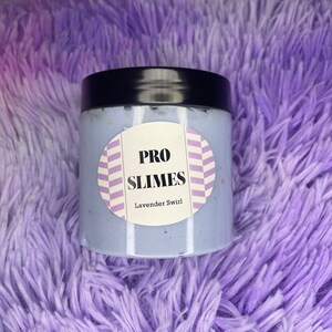 May include: A clear plastic jar with a black lid filled with a light blue slime. The jar has a white label with the text "PRO SLIMES" and "Lavender Swirl" printed on it.