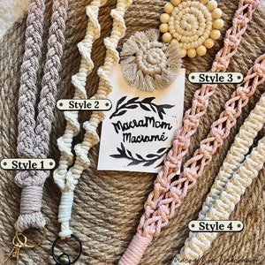 Four styles of boho ID badge lanyards with keychain, laid on top of a jute plate. Style 1 is braided, style 2is a spiral pattern, style 3 is a weave type, and style 4 is a straight braid called square knots. All macrame lanyards are in muted tones.