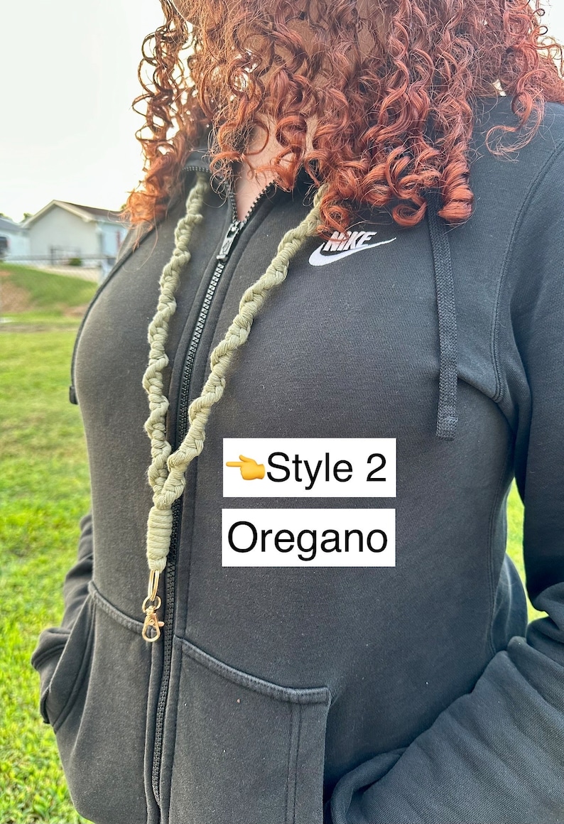 Peut inclure: Un cordon de macram&eacute; vert avec un fermoir dor&eacute;. Le cordon est &eacute;tiquet&eacute; "Style 2 Oregano" dans un encadr&eacute; blanc. La personne sur l'image porte un sweat &agrave; capuche noir.