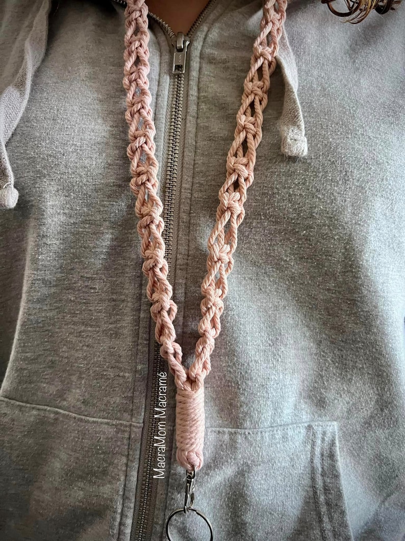 Model wearing style 3, the weaved pattern, in a muted pink color. The keychain clasp reaches around bellybutton area.