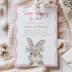 Op de afbeelding: Een roze en witte uitnodiging met een konijn dat een bloemenkrans draagt. De tekst luidt "Some bunny is one" en bevat details voor Sophia's 1e verjaardag.