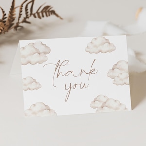 Może przedstawiać: Biała kartka z podziękowaniem z brązowym wzorem chmur w akwareli i tekstem "Dziękuję" w brązowym piśmie odręcznym.