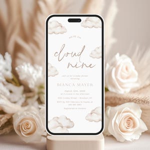 Puede incluir: Una invitación digital para un baby shower con un tema de nubes. La invitación dice "We're on cloud nine" e incluye la fecha, la hora y la ubicación del evento. La invitación está diseñada con un efecto acuarela y presenta una gama de colores marrón claro.