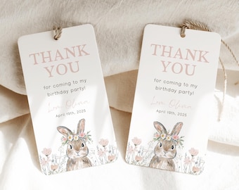 Könnte beinhalten: Zwei rechteckige Geschenkanhänger mit dem Text "THANK YOU" in Rosa. Darunter steht "for coming to my birthday party!" und "Love, Olivia, April 19th, 2025." Jeder Anhänger zeigt eine Illustration eines Hasen mit Blumenkranz.