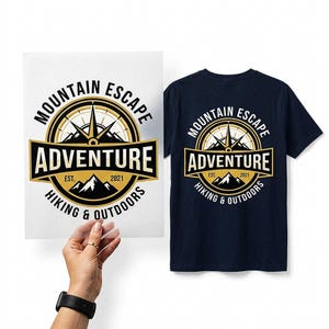 May include: A navy blue t-shirt featuring a graphic print of a compass and mountain range with the text MOUNTAIN ESCAPE ADVENTURE EST. 2021 HIKING & OUTDOORS. The same design is displayed on a transparent sheet held up next to the shirt.