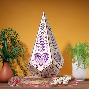 May include: A wooden lamp shaped like a pyramid with intricate cutouts in the shape of hearts. The lamp is illuminated with purple light, creating a warm and inviting glow.