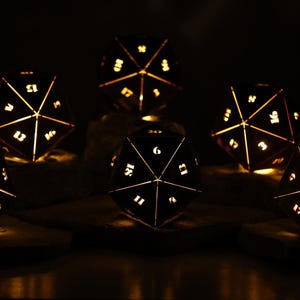 May include: Six illuminated, geometric dice with white numbers and golden light. The dice are arranged on a dark surface, creating a warm, inviting glow against the black background. A unique decorative item for tabletop gaming enthusiasts.