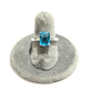 May include: A silver ring with a large, square-shaped, blue gemstone.