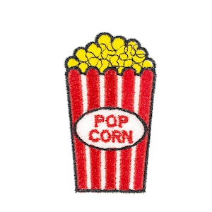 May include: An embroidered patch featuring a classic red and white striped popcorn bucket filled with yellow popcorn. The bucket has a white oval in the center with the red text POP CORN stitched inside. The entire design has a black border.