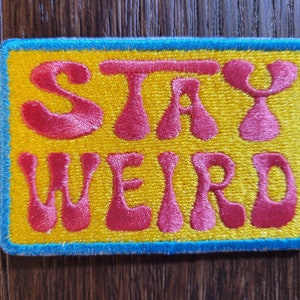 Stay Weird Iron-on or Sew-on Machine Embroidered Patch with Pink Lettering, Yellow Background and Blue Border. Homage to Ms. PacMan