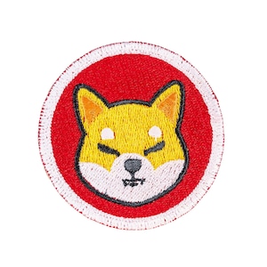 May include: A circular embroidered patch featuring a stylized Shiba Inu dog face with yellow fur, white accents on the cheeks and forehead, and a black nose and mouth. The dog is centered on a solid red background, enclosed by a white stitched border.