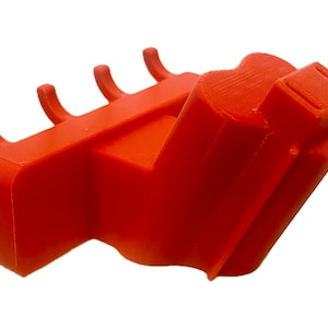 May include: Orange plastic wall mount with five hooks. The hooks are curved and designed to hold items like coats, hats, or bags.