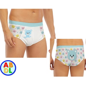 May include: White underwear with a blue waistband and a pattern of colorful teddy bears. A larger blue teddy bear is centered on the front of the underwear.