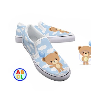 May include: A pair of blue canvas slip-on shoes with a white cloud and brown bear pattern. The bear is holding a blue balloon.